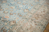 Distressed vintage Khorassan rug with diagonal view of faded sapphire blue and beige floral fields.