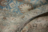 Distressed Khorassan carpet pile, showing rolled border and floral patterns in soft blue and beige.