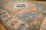 Time-softened abrash across the blue spandrels and wide floral border of an antique Serapi.