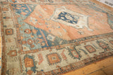 Angled view across the wide geometric border and blue spandrel of an antique Serapi carpet.