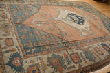 Primitive floral motifs in the wide, abrashed blue and beige border of an antique Persian Serapi.