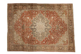 A distressed antique Farahan Sarouk carpet with a large central medallion, rust field, and charcoal floral details.