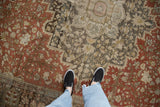 Evenly worn low pile on an antique Farahan Sarouk carpet with rust and charcoal floral motifs.