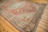 Angled view of a distressed Farahan Sarouk carpet showing the medallion, rust field, and dark borders.