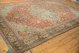 The distressed patina and floral patterns of an antique Farahan Sarouk carpet from an angled perspective.