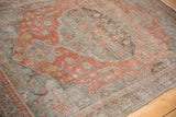 Distressed Malayer rug with muted terracotta, slate blue, and dusty lime green patterns.