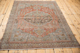 Distressed terracotta, slate blue, and time-softened silver floral patterns on this Malayer rug.