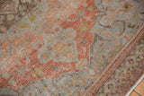 Detail of antique distressed Malayer rug showing terracotta, slate blue floral patterns, worn pile, and outer border.