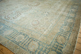 Angled perspective on the distressed texture and low pile of a vintage Tabriz carpet.