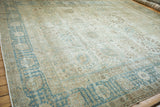 Weeping willow border motif in dusty blue and sand on a distressed vintage Tabriz carpet corner.