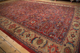 Angled view of a vintage Mahal carpet showing the brick red field and wide palmette border.