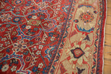 Close-up of a vintage Mahal rug's brick red floral field contrasting with the sand-colored Herati border.