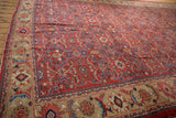 A vintage Mahal carpet's wide, sand-colored Herati border contrasting with the intricate brick-red floral field.