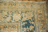 Distressed Khorassan carpet corner, showing faded terracotta and teal palmette border detail.