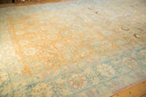 The pale rust field and dusty blue palmette border of a distressed vintage Tabriz carpet.
