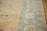 Close view of worn palmette motifs within the pale rust field and dusty sky blue border.