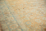 A vintage Tabriz carpet's dusty blue palmette border contrasting with its distressed pale rust field.