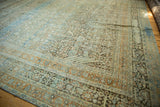 Distressed vintage Tabriz carpet corner, showcasing signature cartouche border and soft blue, terracotta abrash.