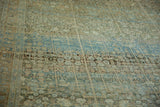 Angled detail of a distressed Tabriz carpet with blue and rust triple columns and vine motifs.