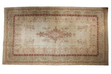 Distressed hand-knotted Kerman carpet, faded ivory field, floral medallion, muted Safavid borders.