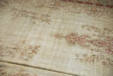 Distressed antique ivory Kerman carpet field, showing faded red floral bouquets and wear.