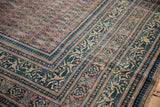 Distressed antique Serbend carpet: worn aubergine boteh and navy blue bordered field.