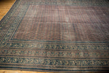 Antique Serbend carpet border showing time-softened aubergine, blush, and navy botanical motifs.