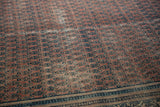 Close-up of distressed Serbend carpet showing dusty aubergine boteh motifs with visible foundation wear.