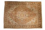 Vintage distressed Heriz carpet with a central starburst medallion and floral patterns in soothing sand and ivory tones.