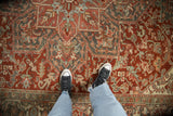 A close view showing the even wear and intricate geometric patterns of a distressed Persian Heriz carpet.