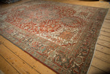 Angled view of a vintage Heriz carpet showing the large geometric medallion and evenly worn pile.