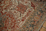 Intricate turtle samovar and vine motifs on the border of a vintage distressed Heriz carpet.