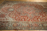 Angled view across the cherry red field and geometric medallion of a vintage Heriz carpet.