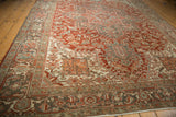 A distressed Persian Heriz carpet's interconnected turtle and vine border shown from a low angle.