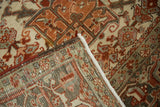 Folded corner of a distressed Heriz carpet showing the hand-knotted back and low-pile front.