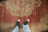 Distressed antique Bijar carpet's central palmette medallion, abrashed faded red field, Herati motifs.