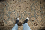 Distressed vintage Tabriz carpet texture featuring slate blue, beige, and oxidized silver floral motifs.