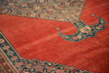 A bat-shaped medallion finial against the madder red field of an antique Bijar carpet.