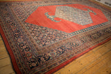 Low-angled view of an antique Bijar carpet highlighting its abrashed red field and hexagonal medallion.