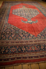 Expansive view of an antique Bijar carpet's abrashed red field, central medallion, and complex navy blue border.