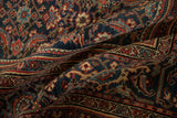 Softly draped antique Bijar carpet showing the dense pile and intricate Herati motif in navy, red, and teal.