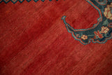 A bat-shaped finial detail against the naturally abrashed madder red field of an antique Bijar.