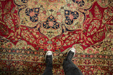 Scale view of an antique Kerman carpet's intricate floral sprays on a cochineal red field.