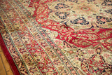 Angled view of the fine lotus flower motifs in the main border of an antique Persian Kerman rug.