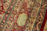 The signature cartouche in dusty blue within the antique Kerman's red and ivory floral border.