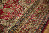 Intricate lotus flower border in ivory and navy on a cochineal red antique Kerman carpet.