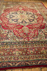 Angled view down the red field of an antique Kerman carpet towards its intricate starburst medallion.