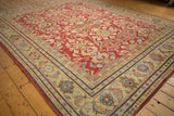 Angled view of a distressed Mahal carpet's cherry red floral field and multi-layered saffron border.