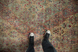 Overhead view of a vintage Kerman carpet's time-softened pile and its intricate floral lattice design.