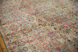 Close-up on the distressed Kerman's thousand flower motif in raspberry, blue, and sand tones.